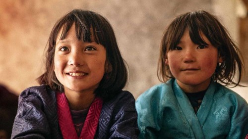 Two smiling children with brown hair and eyes look just past the viewer
