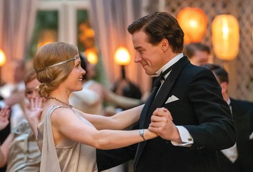 A young man and woman dance, facing each other while holding hands. They're wearing old fashioned but very smart clothes.